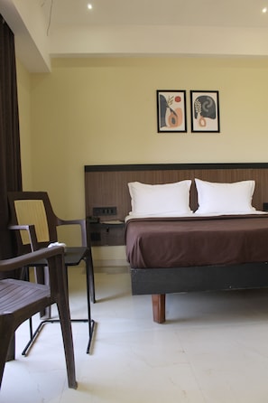 Una habitación de hotel con una cama, un escritorio, una silla y dos obras de arte enmarcadas en la pared.