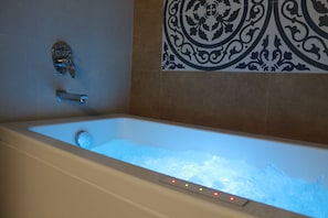 Una bañera con panel de control, grifo y ducha.