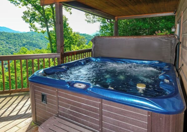 A hot tub on a wooden deck with a view of a forested area. - Riversong Retreat | Pet-Friendly Gatlinburg Cabin with Mountain Views & Game Roo (Sevierville)