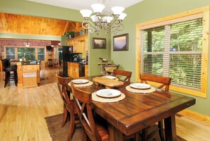 A spacious dining area with a wooden table set for four, surrounded by chairs. - Riversong Retreat | Pet-Friendly Gatlinburg Cabin with Mountain Views & Game Roo (Sevierville)