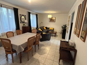 Een woonkamer met een bank, eettafel, stoelen en een bijzettafeltje.