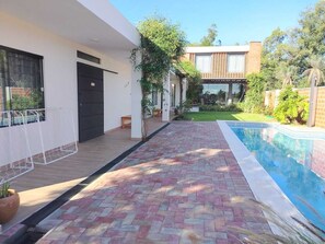 A modern house with a swimming pool, a paved patio, and a well-maintained garden.