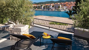 Eine Terrasse mit Blick auf ein Gewässer, ein Tisch mit Getränken und Sitzgelegenheiten im Freien.