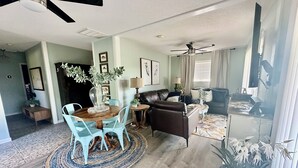 Ein geräumiges Wohnzimmer mit Essbereich, Kamin und Deckenventilator.
