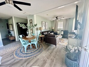 Ein geräumiges Wohnzimmer mit Essbereich, Kamin und Deckenventilator.