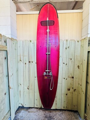Ein roter Duschkopf an einer Holzwand.