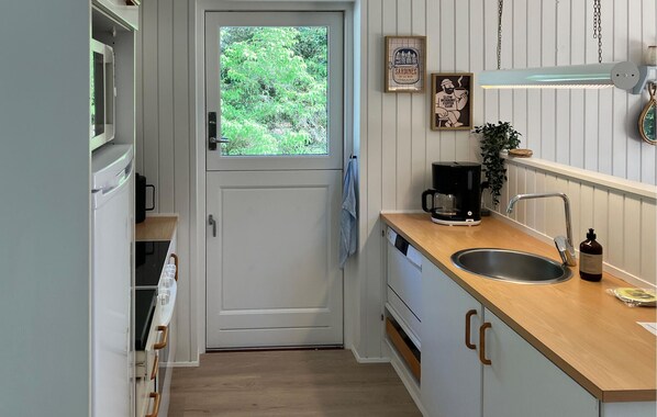 Una cucina compatta con finestra, una macchina da caffè e un lavandino.