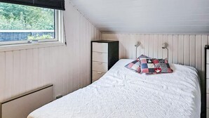 Ein Schlafzimmer mit Bett, Fenster, Kommode und Heizkörper.
