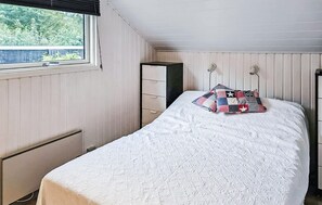 Ein Schlafzimmer mit Bett, Fenster, Kommode und Heizkörper.