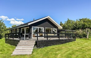 Ein modernes Haus mit einer großen Terrasse, einer überdachten Veranda und einer Treppe zum Eingang.