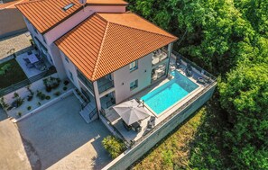 Ein mehrgeschossiges Gebäude mit Schwimmbad, Außenbereich zum Sitzen und einem Garten.