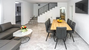 A modern living room with a sofa, a coffee table, and a dining area with a wooden table and chairs. - Beautiful home in Nova Vas (Nova Vas)