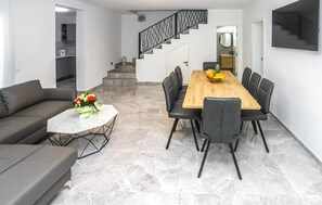 Ein modernes Wohnzimmer mit einer Couch, einem Couchtisch und einem Essbereich mit einem Holztisch und Stühlen.