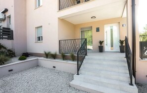 Ein Gebäudeeingang mit Treppe, Metallgeländer und einer Tür mit einem Schild darüber.