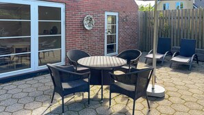 A patio with a round table and four chairs, a brick wall, and a wooden fence. - Lovely home in Ulfborg with WiFi (Ulfborg)