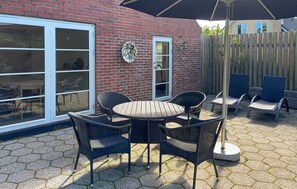 A patio with a round table and four chairs, a brick wall, and a wooden fence. - Lovely home in Ulfborg with WiFi (Ulfborg)