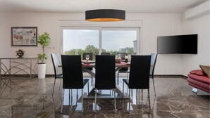 A modern dining area with a glass table, black chairs, a black pendant light, and a large window with a view. - Stunning home in Krnica (Krnica)