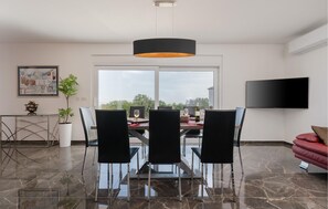 A modern dining area with a glass table, black chairs, a black pendant light, and a large window with a view. - Stunning home in Krnica (Krnica)