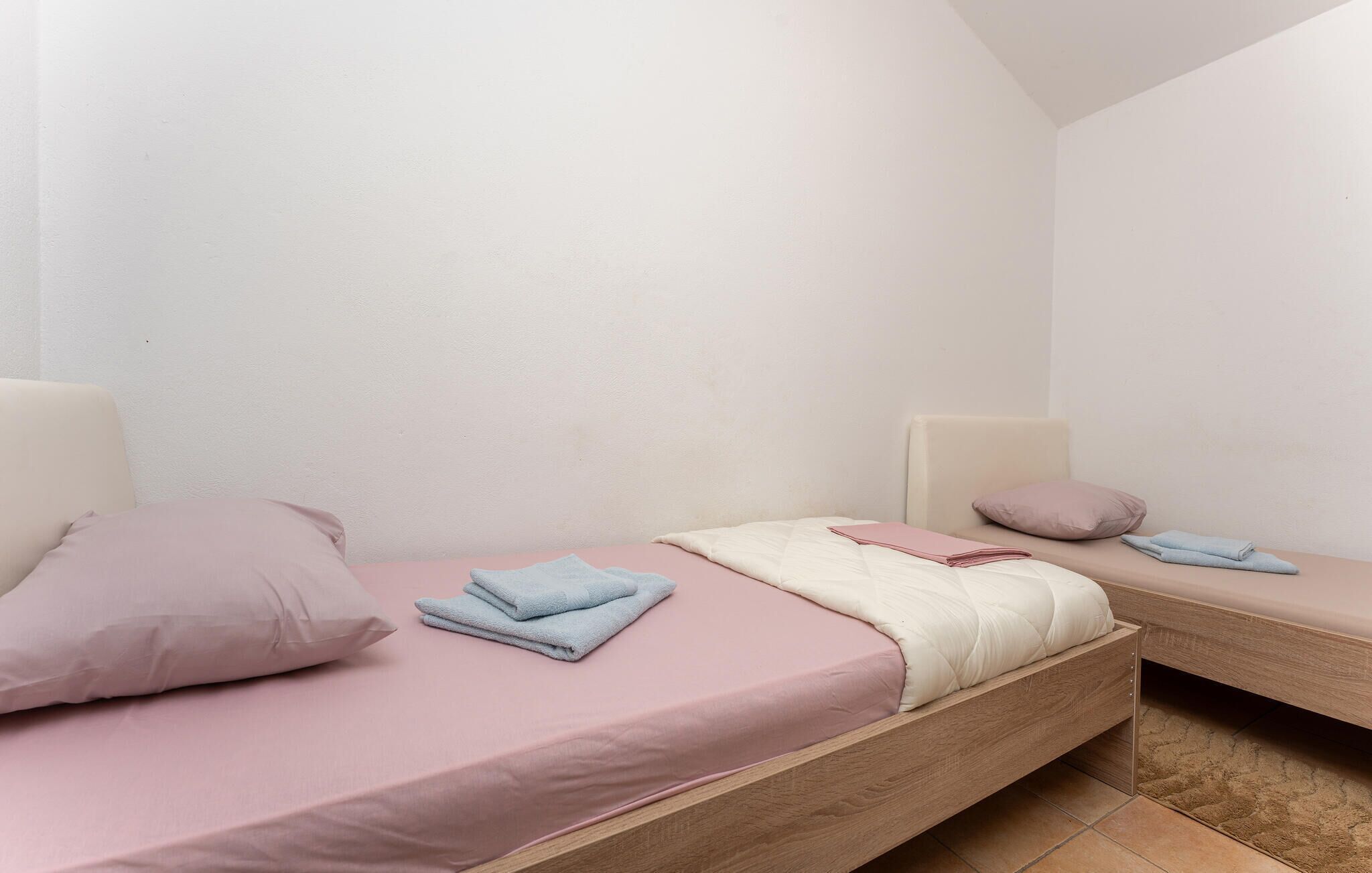 A bedroom with two beds, each with a pillow and a folded towel.