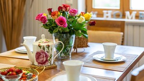 Un tavolo da pranzo con un teiera, un vaso di rose e una tazza su un piattino.