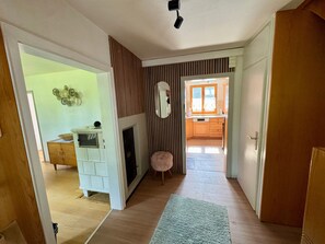 A hallway leading to a kitchen with a window, a fireplace, and a decorative wall piece.