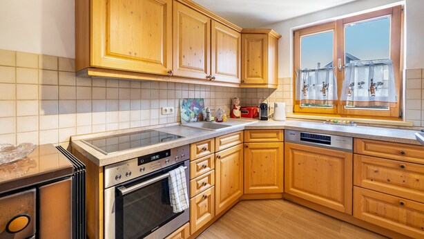 Una cucina con mobili in legno, un forno Siemens, una lavastoviglie e una finestra con vista.