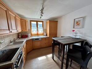 A kitchen with wooden cabinets, a stove, a sink, and a window with curtains.