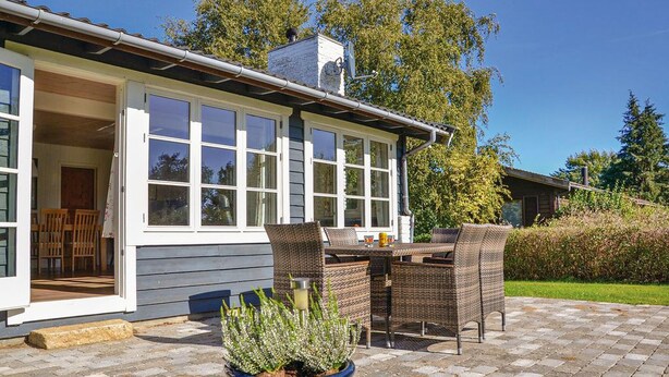 A house with a patio, wicker furniture, and a potted plant.