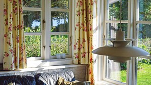 A room with a window seat, floral curtains, and a hanging lamp.