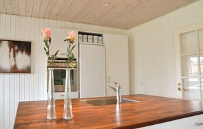 Een keuken met houten aanrecht, een RVS spoelbak en een koelkast.
