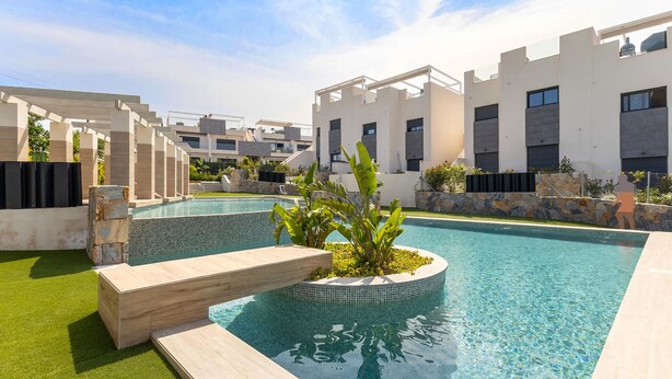 A modern pool area with a clear pool, a small waterfall feature, and a stone wall with plants. - Beautiful apartment in Torrevieja with WiFi (Torrevieja)