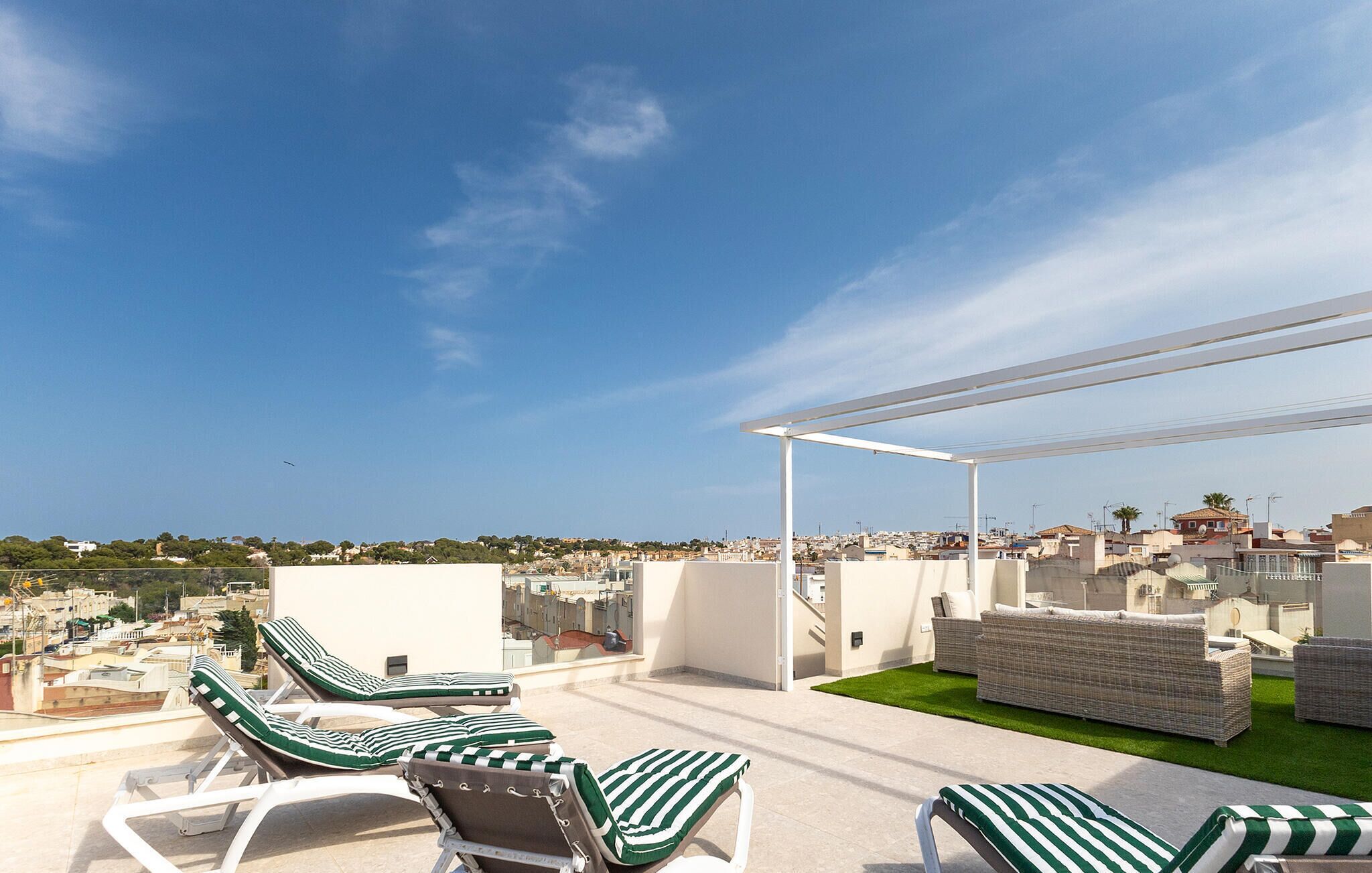 En takterrass med solstolar och en pergola, med utsikt över stadsbilden.