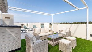 A rooftop patio with wicker furniture, a glass table, and a view of the cityscape. - Beautiful apartment in Torrevieja with WiFi (Torrevieja)