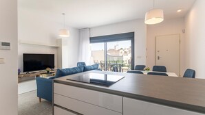 A modern living room with a flat-screen TV, sofa, dining table, and chairs. - Beautiful apartment in Torrevieja with WiFi (Torrevieja)