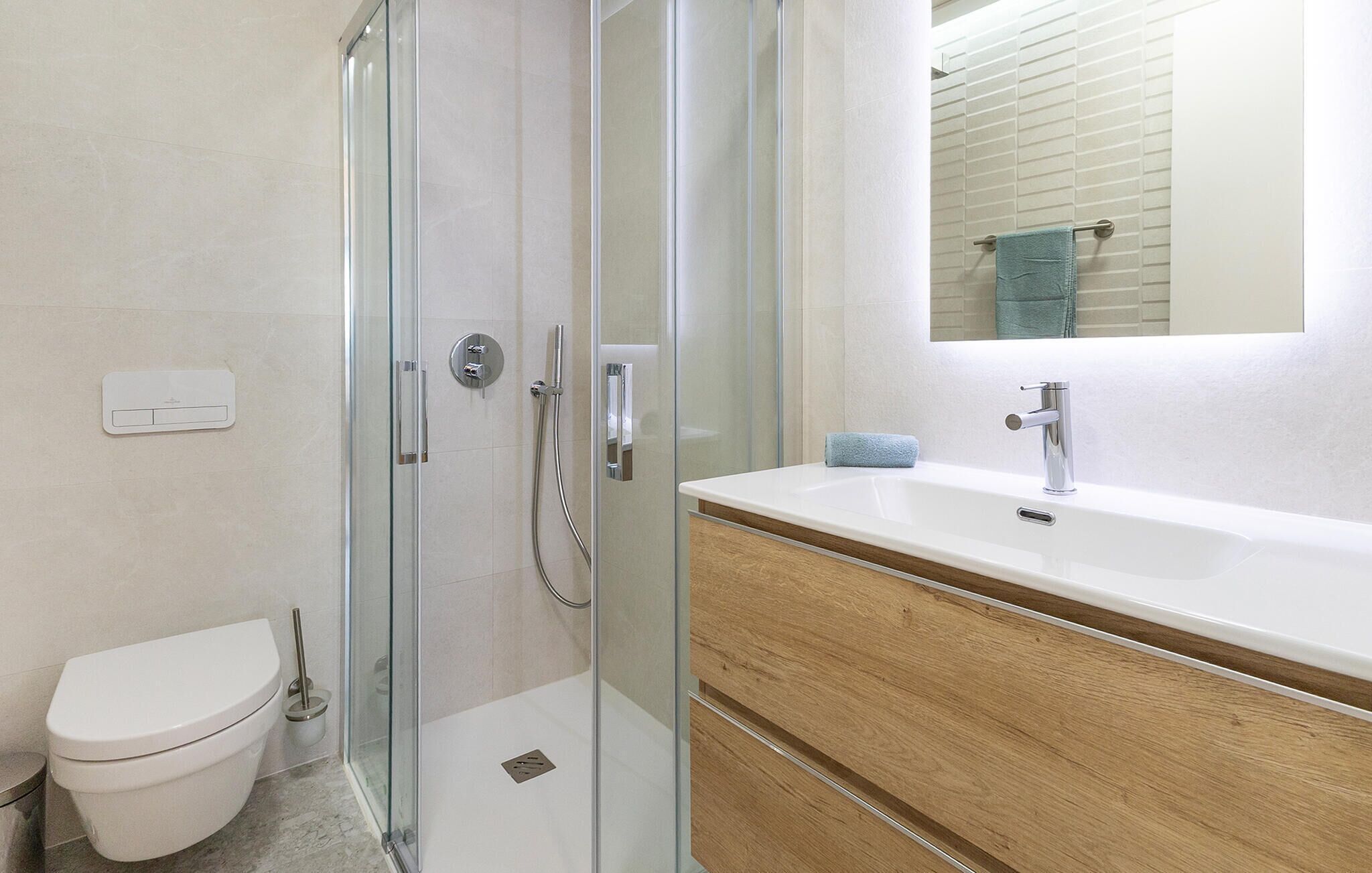 A modern bathroom with a glass-enclosed shower, a white toilet, a wooden vanity with a sink, and a mirror above the vanity.