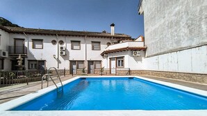 Ein Swimmingpool mit weißem Sonnendeck, umgeben von einem weißen Gebäude mit mehreren Fenstern und Balkonen.