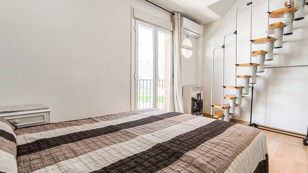 Ein Schlafzimmer mit Bett, Nachttisch, Kleiderschrank und einem Fenster mit Vorhängen.