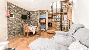 Ein gemütliches Wohnzimmer mit Kamin, einem Essbereich mit Stühlen, einer Treppe und einem Bücherregal.