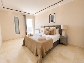 Um quarto com cama, mesas de cabeceira, janela e vista.