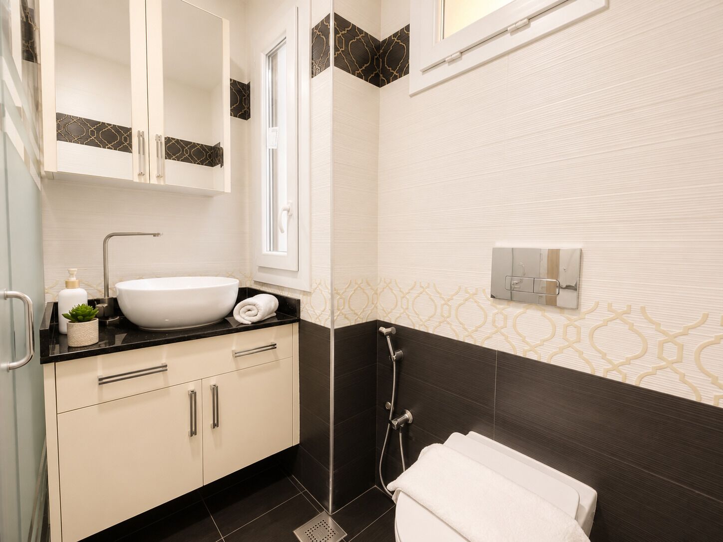 A modern bathroom with a white sink, dark tiles, and a shower.