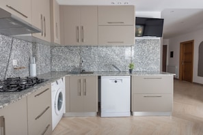 A modern kitchen with a built-in washer, stainless steel appliances, and light wood cabinetry.
