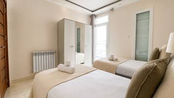 Habitación de hotel con dos camas, un radiador, un espejo grande y una ventana con persianas.
