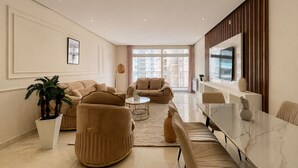 Ein modernes Wohnzimmer mit einer Couch, Sesseln, einem Couchtisch und einem Esstisch.
