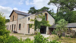 A rustic stone building with a sloped roof, a large door, and a small porch. - Tastefully renovated 18th century farmhouse, landscaped gardens and access to the château grounds (Treillières)
