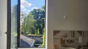 A kitchen with a large window, a round sink, and a tiled backsplash. - Tastefully renovated 18th century farmhouse, landscaped gardens and access to the château grounds (Treillières)