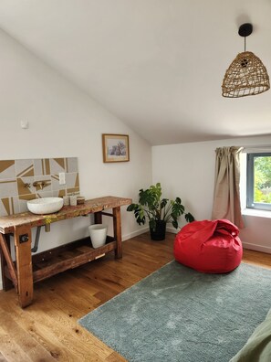 A room with a wooden table, a red bean bag, a potted plant, a window with curtains, and a hanging light fixture. - Tastefully renovated 18th century farmhouse, landscaped gardens and access to the château grounds (Treillières)