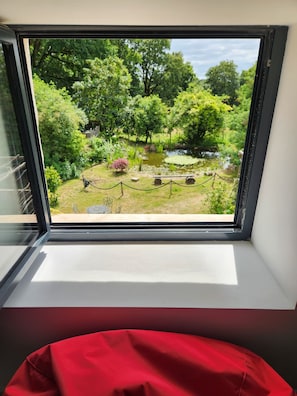 A window with a view of a garden, including a pond and trees. - Tastefully renovated 18th century farmhouse, landscaped gardens and access to the château grounds (Treillières)