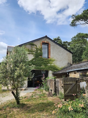 A two-story building with a stone facade, a large window, and a wooden gate. - Tastefully renovated 18th century farmhouse, landscaped gardens and access to the château grounds (Treillières)