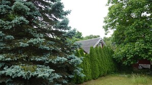 A house surrounded by dense evergreen trees and a well-maintained lawn. - Lychenlodge on Oberpfuhl Lake with canoe & fireplace (Lychen)