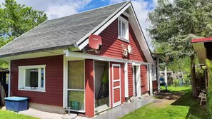 Un bâtiment rouge avec un toit en pente, une antenne parabolique et un petit porche.